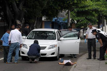 El cadáver de Claudia de Medina yace en el suelo mientras la policía investiga el automóvil atacado