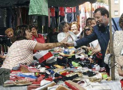 Rajoy saluda a una vendedora de un mercadillo de Guadalajara durante su visita ayer a esta ciudad.