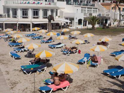 Varias personas toman el sol en la Cala Santandría de Menorca. 