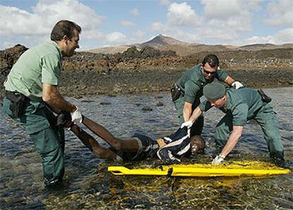 Agentes de la Guardia Civil tratan de sacar del agua a uno de los africanos que fallecieron ayer en el naufragio en Fuerteventura.