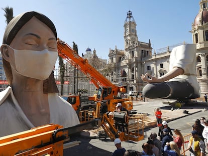 Operarios colocan una mascarilla a la falla del Ayuntamiento, este miércoles en Valencia.