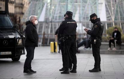 Un hombre habla con varios policías nacionales en la Puerta del Sol, en Madrid (España), a 30 de diciembre de 2020.