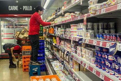 Empleados de un supermercado de Buenos Aires acomodan productos en los estantes, el 14 de marzo de 2023.