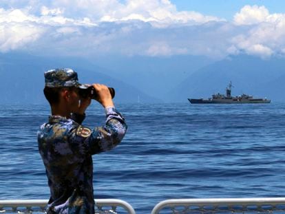 Un miembro de la Armada china observa con sus prismáticos durante las maniobras militares puestas en marcha por Pekín. Al fondo, una fragata taiwanesa.