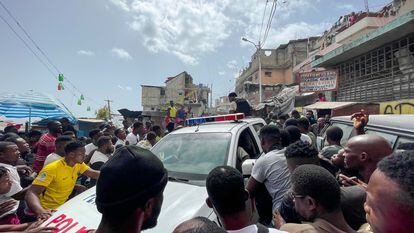 Decenas de personas se aglomeran en torno a un automóvil de la Policía en el que hay dos colombianos capturados por un grupo de personas en Puerto Principe (Haití).