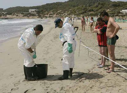 Varios operarios limpian de residuos contaminantes la playa de En Bossa (Ibiza).