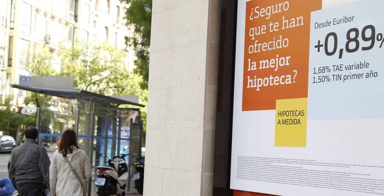 Dos personas pasan junto a un anuncio hipotecario en Madrid.