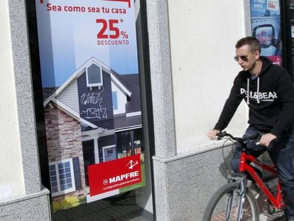 Un ciclista pasa delante de una oficina de Mapfre, en Madrid.
