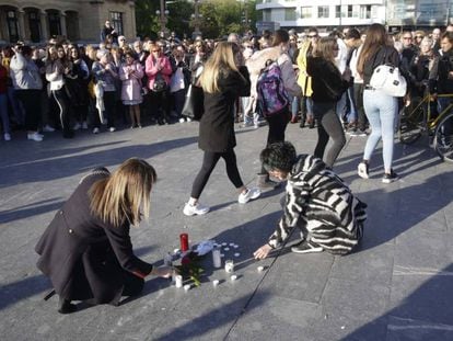 Dos mujeres ponen velas en la concentración de repulsa por la muerte en una pelea de un menor en San Sebastián.