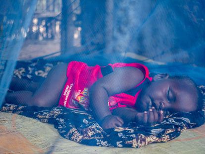 Un bebé nacido en Dadaab duerme sobre el suelo de su casa, protegido por una mosquitera.
