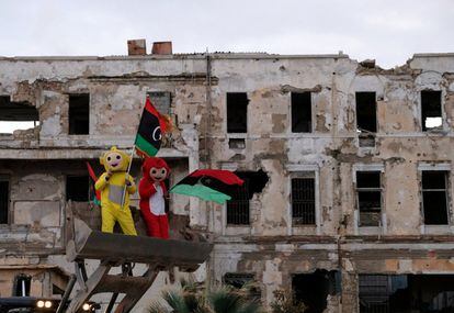 Dos personas disfrazadas portan banderas libias durante la celebración del octavo aniversario de la revolución libia, en Bengasi.