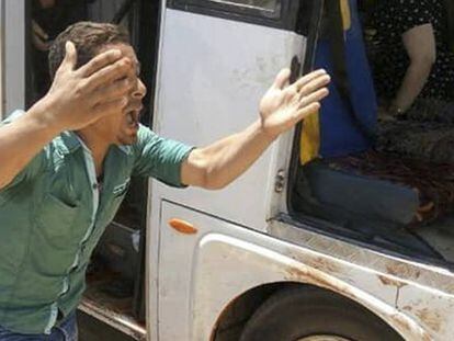 Un hombre grita junto al autobús que transporta a un grupo de coptos atacado este viernes en las afueras de El Cairo.