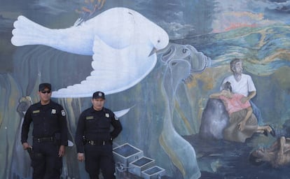 Policías salvadoreños detrás de un mural que hace alusión a la guerra civil que sufrió El Salvador.