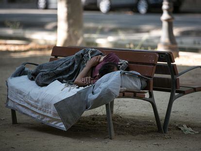Una persona sin hogar duerme en un banco del paseo Picasso en Barcelona.
