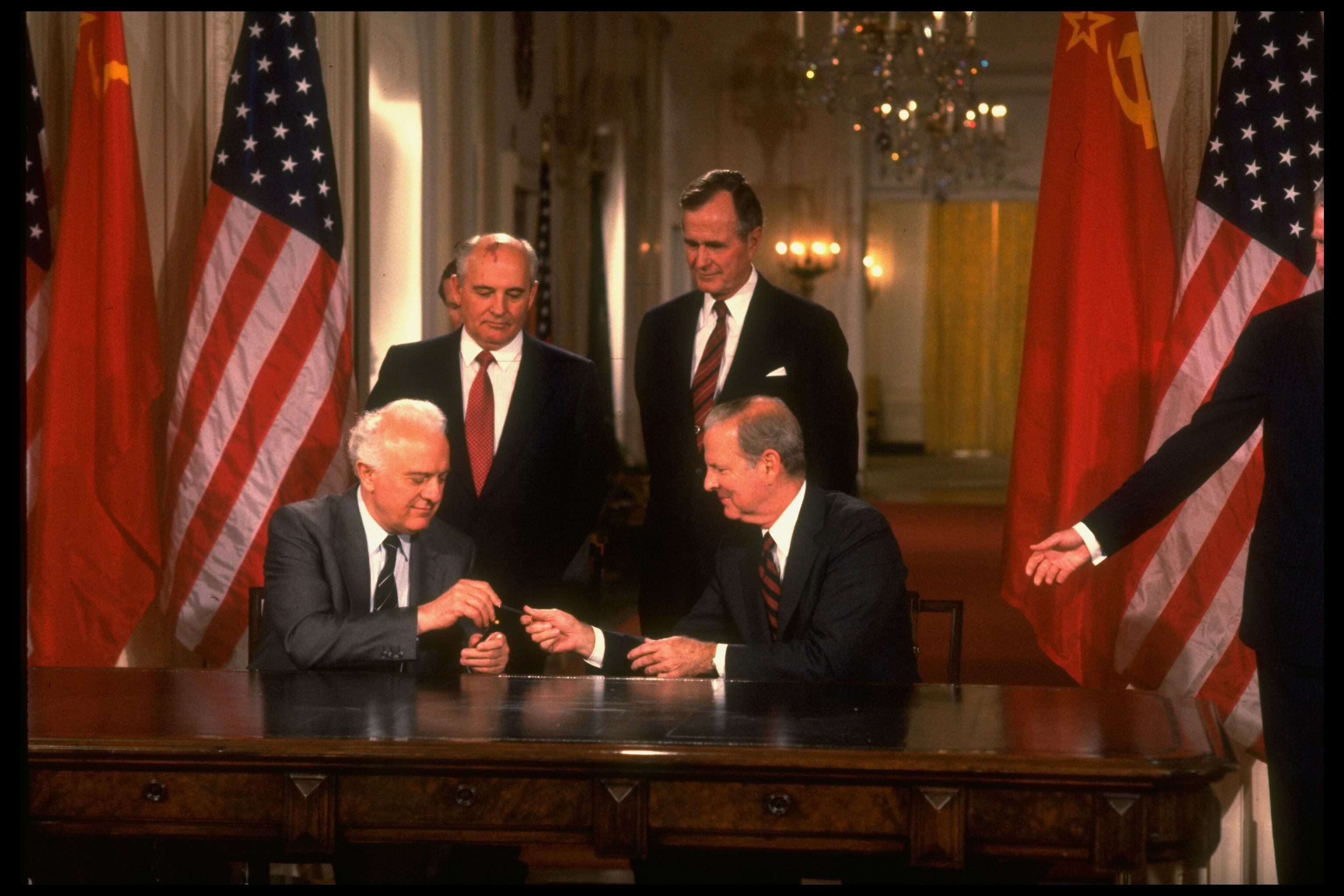 Eduard Shevardnadze (izquierda, sentado), ministro de Exteriores de la URSS en 1990, intercambia una estilográfica con James Baker, secretario de Estado de EEUU. Detrás, Mijail Gorvachov y George Bush.