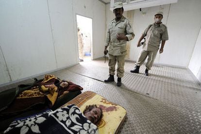 Dos guardias vigilan los cuerpos de Gadafi (derecha) y su hijo Mutasim en un mercado de Misrata.