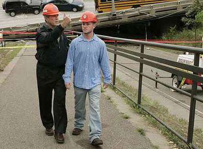 Bush visita el puente hundido en Minneapolis junto a Gary Babineau, que ayudó a salvar a los niños que iban en el autobús que se ve al fondo.