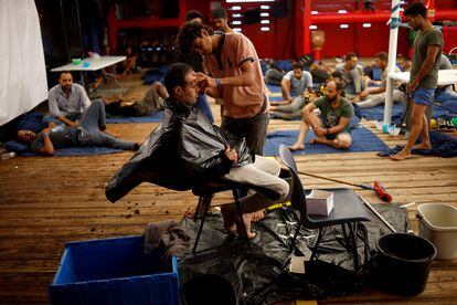 Said Hussam, un peluquero egipcio de 20 años, corta el cabello a uno de los 99 migrantes a bordo del bote, el pasado  21 de agosto.