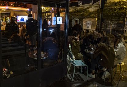 Clientes en un café de París siguen este miércoles el discurso televisado del presidente Macron en el que anuncia un nuevo confinamiento en Francia.