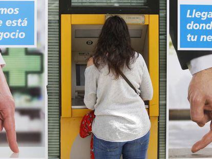 Una joven utiliza un cajero automático en una oficina bancaria, en Madrid.