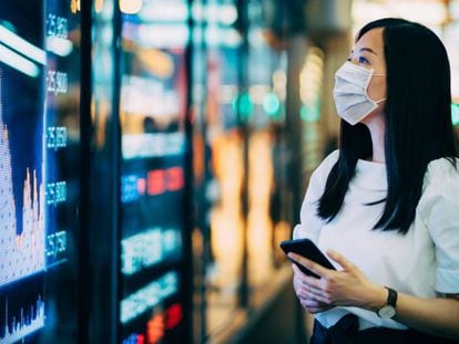 Una inversora consulta la evolución de las Bolsas en una pantalla en el distrito financiero de Hong Kong.