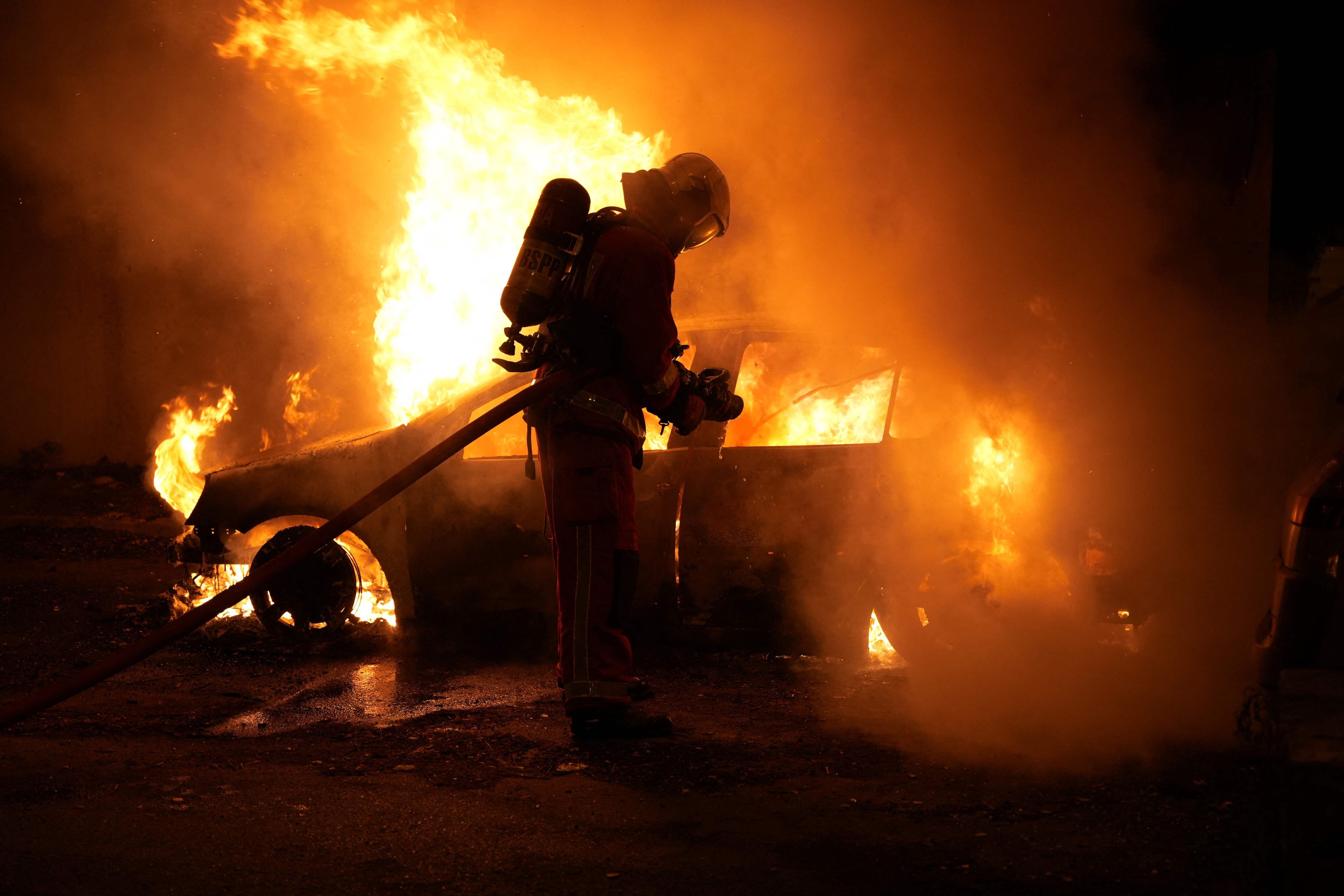 Un bombero apaga un vehículo en llamas durante las protestas en Nanterre, el miércoles.