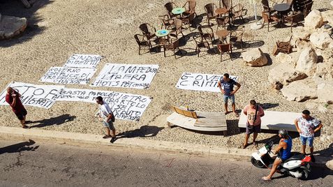 Residentes de Lampedusa ponen pancartas en señal de protesta contra el Gobierno central ante la falta de gestión de la inmigración en la isla, este lunes.
