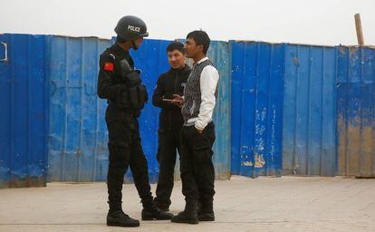 Un policía chino habla con dos ciudadanos en Kashgar (Xinjiang), en marzo de 2017.