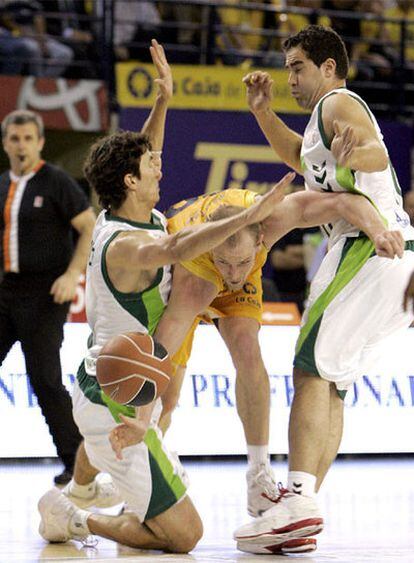 El alero del Kalise Gran Canaria, Jim Moran (centro), pelea por un balón ante los jugadores del Unicaja Málaga, el base Carlos Cabeza (derecha) y el escolta Rodríguez.