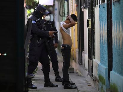 Un agente de la policía registra a un hombre en Soyapango, El Salvador.