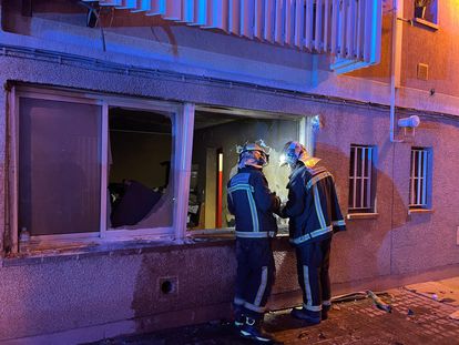Dos bomberos, ante la ventana del piso incendiado en Aranjuez.