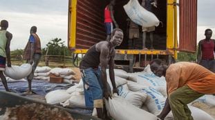 FILE - In this Thursday, June 26, 2014 file photo, workers offload sacks of cereals from the World Food Program (WFP) from a truck in Minkaman, South Sudan. The World Food Program on Friday, Oct. 9, 2020 won the 2020 Nobel Peace Prize for its efforts to combat hunger and food insecurity around the globe. (AP Photo/Matthew Abbott, File)
