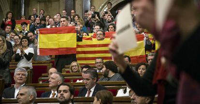 El líder del PP català, Xavier García Albiol, sosté una bandera espanyola enmig d'algunes senyeres durant el ple del Parlament.