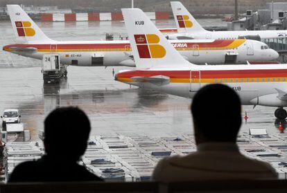 Dos pasajeros observan varios aviones de Iberia, en Barajas.