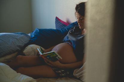 Una mujer embarazada lee un cuento en la cama.