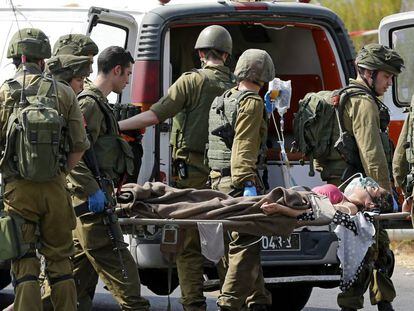 Miembros de las fuerzas de seguridad israel&iacute;es trasladan a uno de los heridos del atropello en Hebr&oacute;n.