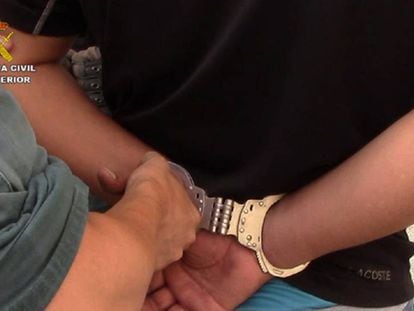 Un agente de la Guardia Civil esposa a unos de los detenidos por introducir ilegalmente a 600 personas desde Marruecos. 