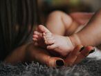 Una madre sujeta los pies de su recién nacido.