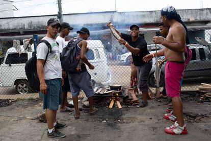 Un grupo de venzolanos asa pescado en una calle aledaña a la estación de autobuses de Manaos (Brasil).