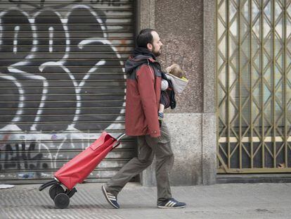 Un pare amb el seu nadó i un carro d'anar a comprar, a Barcelona durant l'estat d'alarma.