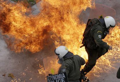 Las llamas rodean a varios agentes de la policía griega tras los enfrentamientos con un grupo de radicales durante la jornada de huelga general en la plaza Syntagma de Atenas (Grecia).