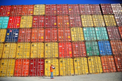 Un trabajador portuario examina contenedores en un muelle.