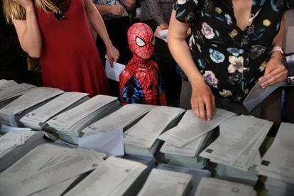 Un niño disfrazado de Spiderman permanece junto a la mesa donde se encuentran las papeletas electorales, en un colegio de Madrid.