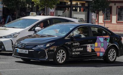 Un vehículo de transporte con conductor (VTC) de la empresa Cabify circula junto a un taxi, en Madrid.
