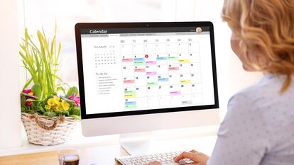 Una mujer utilizando una aplicación de calendario en un ordenador de sobremesa.