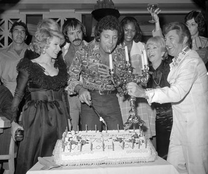 Liberace que sujeta un candelabro mientras el cantante Tom Jones (c) sopla las velas durante su cumpleaños junto a (de izquierda a derecha); Joan Rivers, Sonny Bono, Dionne Warwick y Debbie Reynolds en el Caesars Palace en Las Vegas (Estados Unidos) el 5 de junio de 1974.