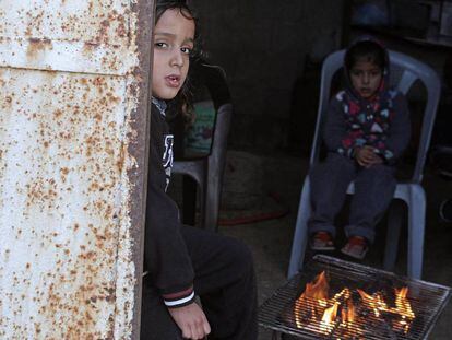 Ni&ntilde;os palestinos se calientan con un brasero en el campamento de refugiados de Al Shateaa, en Gaza. 