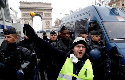 Un manifestante de los 'chalecos amarillos' sostiene una flor frente a un grupo de gendarmes durante la manifestación en París.