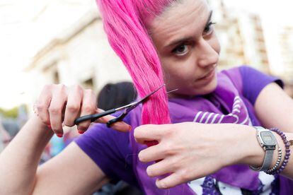 Una joven se corta el pelo en solidaridad con las mujeres iraníes, durante la manifestación del 8M en Valencia. 