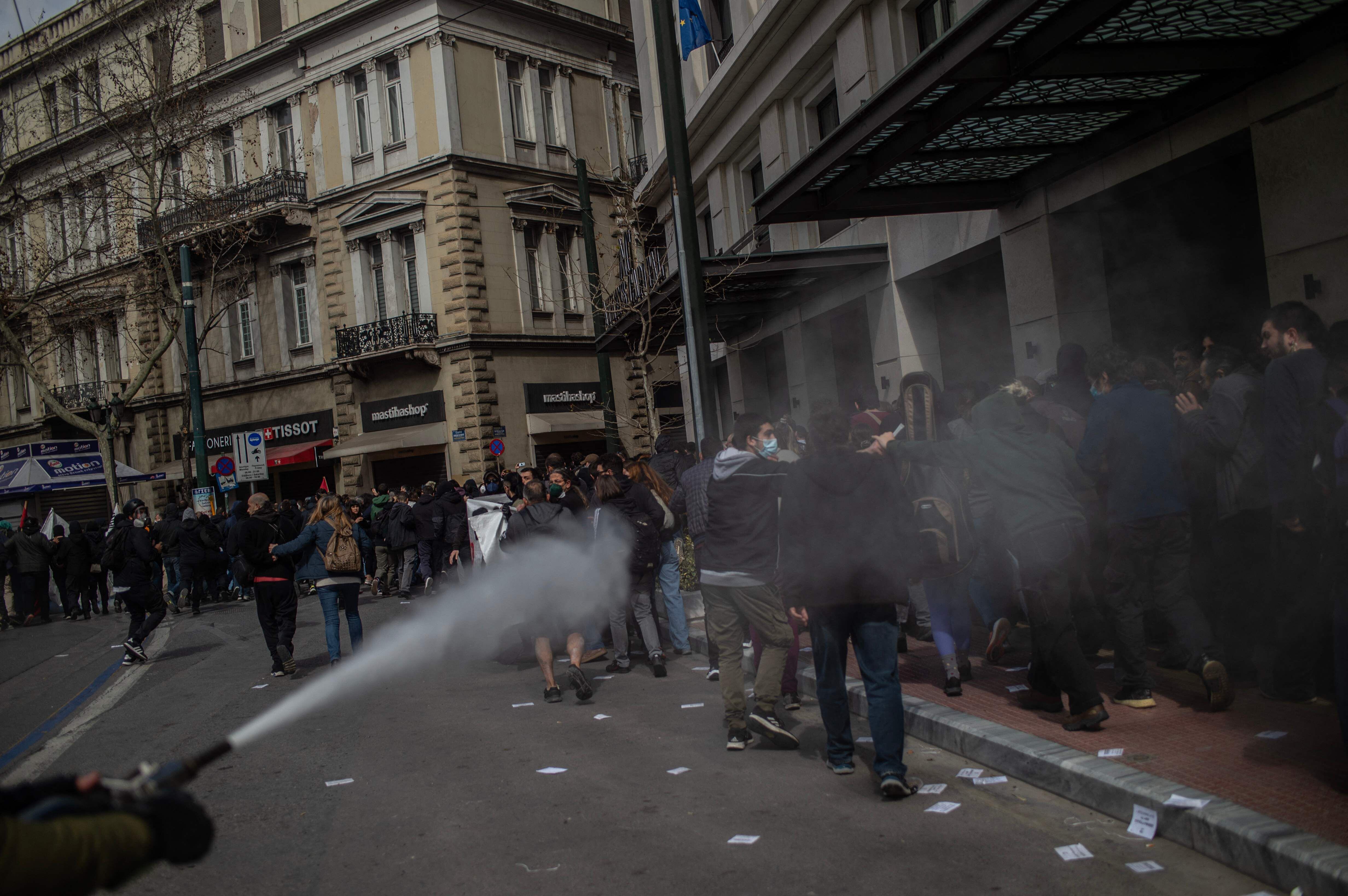 Policía antidisturbios rocían con cañones de agua a los manifestantes que han protestado este jueves en Atenas, coincidiendo con la jornada de huelga general en todo el país.